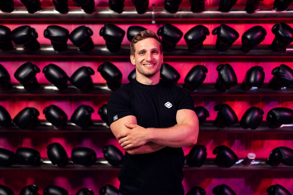 Man in Black Crew Neck T-shirt Standing in Front of Boxing Gloves